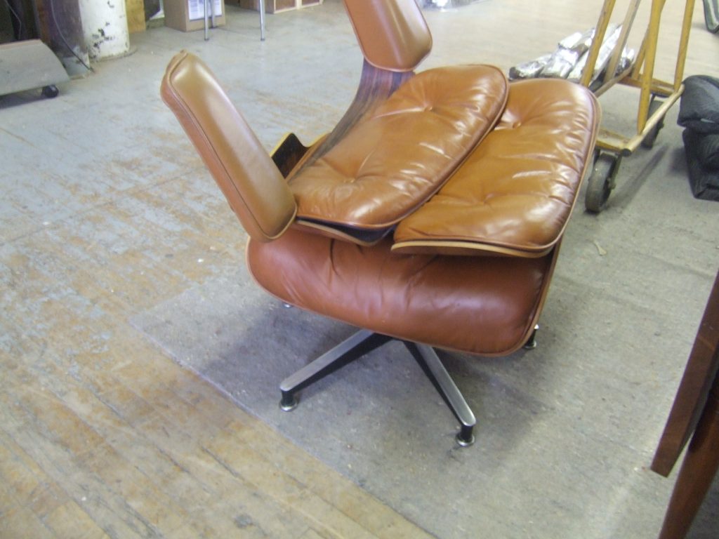 Eames Lounge Chair with damaged leather and worn shock mounts before restoration by Olek Inc.